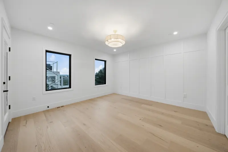 Bedroom with raised-panel accent wall and chandelier at Residence 3, 421 East Sixth, South Boston