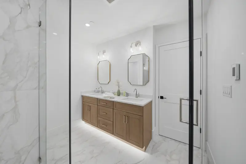 Marble-look primary bath with double wood vanity and glass shower at Residence 4, 421 East Sixth, South Boston