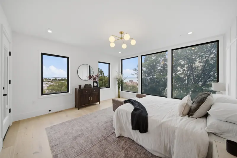 Bedroom with large black-framed windows and treetop views at Residence 4, 421 East Sixth, South Boston